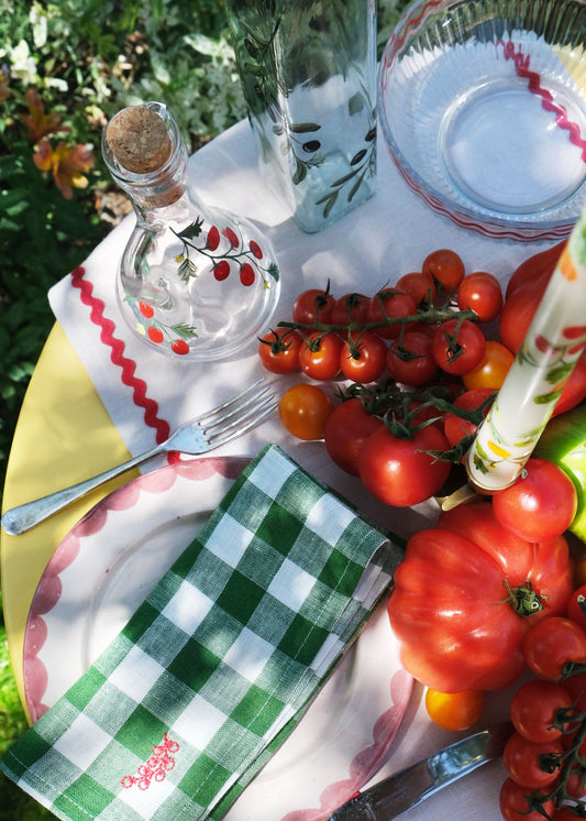 Outdoor setting with fresh tomatoes, greenery, and a checkered napkin