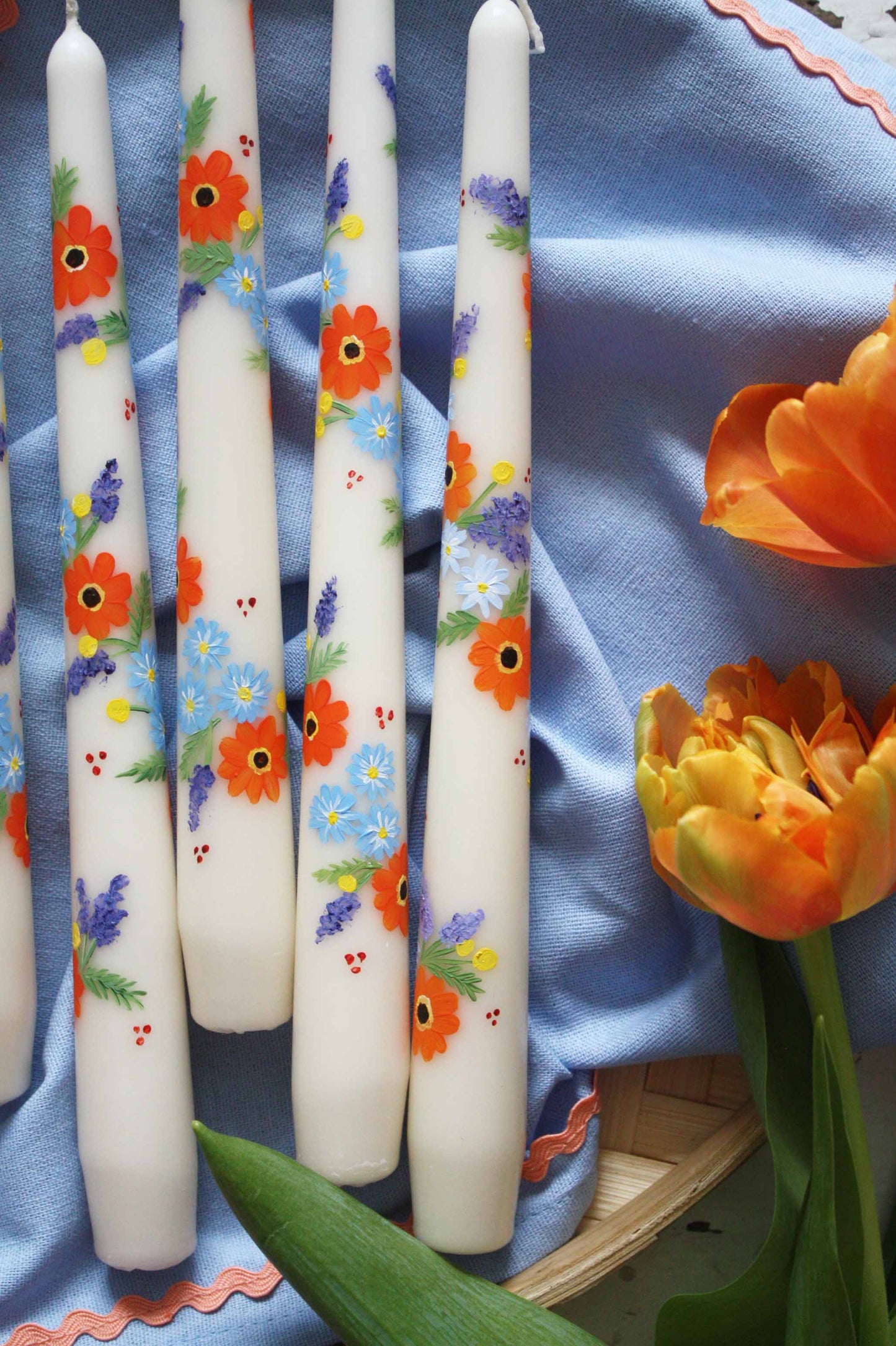 orange and blue flowers hand painted onto ivory candle