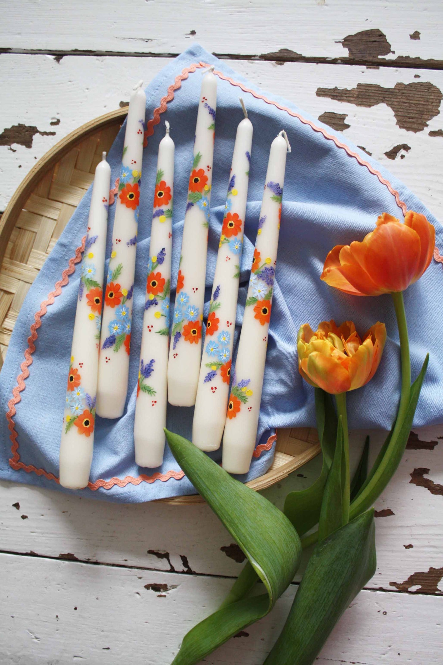 orange and blue flowers hand painted onto ivory candle